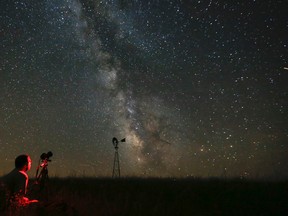 In this Wednesday, July 23, 2014 file photo, Omaha photographer Lane Hickenbottom photographs the night sky in a pasture near Callaway, Neb. With no moon in the sky, the Milky Way was visible to the naked eye. More than one-third of the world’s population can no longer see the Milky Way because of man-made lights, according to a scientific paper by Light Pollution Science and Technology Institute's Fabio Falchi and his team members, published on Friday, June 10, 2016. (Travis Heying/The Wichita Eagle via AP)