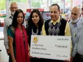This June 2012 file photo provided by WMAQ-TV in Chicago, shows Urooj Khan, centre, holding a ceremonial check in Chicago for US$1 million as winner of an Illinois instant lottery game. At left, is Khan's wife, Shabana Ansari.  (Courtesy of WMAQ-TV in Chicago via AP, File)