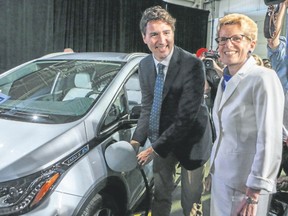 Prime Minister Justin Trudeau, along with Ontario Premier Kathleen Wynne, plugs in a Chevrolet Bolt electric car in Oshawa on June 10, 2016. (Dave Thomas/Toronto Sun)