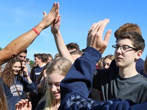Tim Miller/The Intelligencer
Harry McMurtry high-fives students from St. Theresa Catholic Secondary School as they file out of Titan Field after walking a mile with him on Friday in Belleville. McMurtry made a stop at the school on his walk from New York to Toronto to raise money for Parkinson's research.