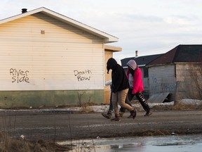 Teenage girls walk through the streets in the northern Ontario First Nations reserve in Attawapiskat, Ont., on Monday, April 16, 2016. THE CANADIAN PRESS/Nathan Denette