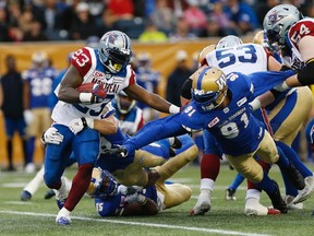 Montreal Alouettes' Brandon Rutley (23) straight-arms Winnipeg Blue Bombers' Adrian Hubbard (91) but gets hauled down by Ian Wild (38) during the first half of pre-season CFL action in Winnipeg Wednesday, June 8, 2016. THE CANADIAN PRESS/John Woods