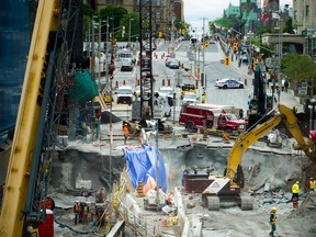 Construction crews were at work Sunday June 12, 2016 as pedestrians and shoppers got a peek of the status of the sinkhole from the pedestrian bridge. (Ashley Fraser/ Postmedia Network)
