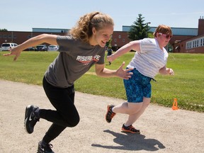 Natalie Martinez, left, and Best Buddies pal Kennedy Trollope train at  Western University?s TD Stadium. The two Westminster school students are part of a unique partnership, teaming 20 recreational leadership students like Martinez with 17 developmental education students in a fitness class. (MIKE HENSEN, The London Free Press)