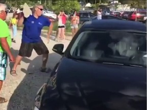 Screenshot from a video shows an unidentified man smashing a late model BMW parked near the Grand Bend beach on Saturday, to free a small dog that had been left in the locked car. The video had been seen by almost 60,000 people by Monday morning. The dog was freed and given water and when Lambton OPP showed up, returned to its owner. OPP and the OSPCA's Huron branch are investigating. Police are also asking the public to exercise discretion in such matters and said it would be better if authorities were first contacted before such damage is done.
(Handout)