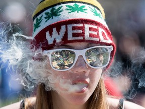 A woman exhales while smoking a joint during the annual 420 marijuana rally on Parliament hill on Wednesday, April 20, 2016 in Ottawa. THE CANADIAN PRESS/Justin Tang