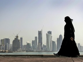 In this May 14, 2010 file photo, a Qatari woman walks in front of the city skyline in Doha, Qatar. A Dutch woman held in Qatar for nearly three months after telling police she had been raped was released Monday after receiving a one-year suspended prison sentence, a Dutch diplomat said Monday. (AP Photo/Kamran Jebreili, File)