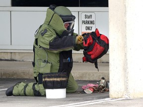 A member of the London Police bomb squad opens a suspicious bag in the parking lot of Westervelt College in London, Ontario on Monday June 13, 2016. (MORRIS LAMONT, The London Free Press)