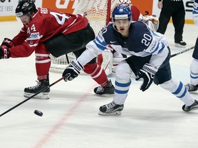 Finland’s Sebastian Aho, centre, and Canada’s Morgan Rilles, left, battle for the puck during the Ice Hockey World Championships final match between Finland and Canada, in Moscow, Russia, on Sunday, May 22, 2016. (AP Photo/Pavel Golovkin)