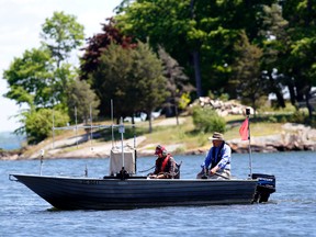 Queens University biology masters student Colleen Burliuk , left, listens for a 'chirp' from a transmitter attached to an American eel on the St. Lawrence River while proffessor john Casselman steers a boat Tuesday, May 31, 2016 east of Rockport, Ont. Darcy Cheek/Brockville Recorder and Times/Postmedia Network