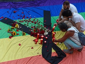 Mourners light candles placed on rainbow flag draped with a black crape outside Barcelona's city hall during a vigil on June 13, 2016, in remembrance of victims after a gunman opened fire in a gay nightclub in Orlando, Florida in the worst mass shooting in U.S. history. AFP PHOTO / JOSEP LAGO