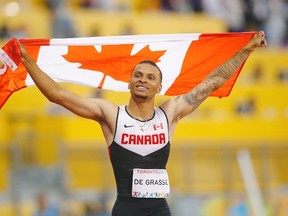 Andre De Grasse, of Canada, holds a flag after he wins the gold medal in the men's 100m final during the athletics competition at the 2015 Pan Am Games in Toronto on Wednesday, July 22, 2015. THE CANADIAN PRESS/Mark Blinch