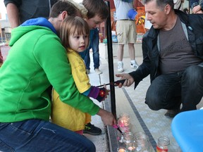 BRUCE BELL/the intelligencer
Picton resident Dan Taylor helps some children light candles during a vigil held in front of Books & Company in Picton Monday night in memory of the victims killed during a mass shooting at Pulse, a gay nightclub in Orlando Florida early Sunday morning.