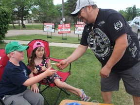 Chris Jobb, who travelled from Prince Albert, Sask. with his family after seeing a Facebook post about how 10-year-old Jayden West was selling juice to help his family pay down a $1,800 electricity bill, hands the youngster a $50 bill in exchange for three cups of juice on Tuesday. He complimented Jayden on his heart and courage for stepping up to help his mom and dad in a tough situation. Saying his family has been "blessed," Jobb said he wanted to do anything he could to help out. (Morgan Modjeski/The Saskatoon StarPhoenix)