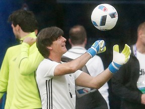 Coach Joachim Low tries goalkeeper gloves during a training session of the German national team in Saint-Denis, France, Wednesday, June 15, 2016. (AP Photo/Michael Probst)