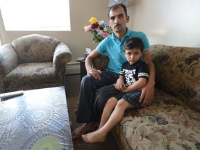 Syrian refugee Ahmad Al Agha sits with his son, Abdel Malek Al Agha, 4, in his south London apartment. Agha says the first apartment provided for his family was uninhabitable and he had to find a new one. (MORRIS LAMONT, The London Free Press)