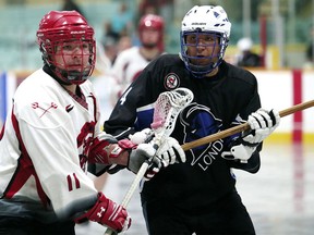 Wallaceburg Red Devils' Preston Whiteye, left, tangles with London Blue Devils' Edwin Brown in the second period Wednesday at Wallaceburg Memorial Arena. (MARK MALONE/The Daily News)