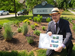 Murray Hunter shows the plan for their gardens4bees around the Siskind?s sign on Colborne Street in London. (MIKE HENSEN, The London Free Press)