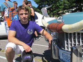 Ben Williams, 18, kneels next to the front of his 1971 Cadillac Coupe de Ville at the track at St. Clair Secondary School during an auto show held on Friday June 17, 2016 in Sarnia, Ont. Williams organized this year's car show, held on the final full day of classes at the city high school set to be consolidated in September with SCITS. (Paul Morden/Sarnia Observer)