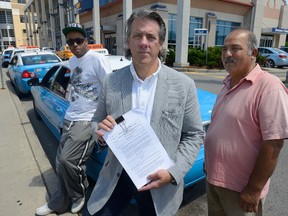 Taxi spokesperson Roger Caranci, centre, with taxi drivers Alain Nzeyimana, left, and Manuchehr Ahmal at the London train station on Friday. Caranci is pleased a city staff report on Uber issues will consider safety a priority. (MORRIS LAMONT, The London Free Press)