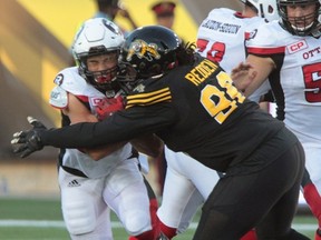 Hamilton Tiger-Cats’ Terry Redden wraps up Ottawa Redblacks running back Kienan Lafrance on June 17 at Tim Hortons Field. (The Canadian Press)