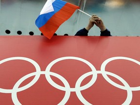 FILE - In this Feb. 18, 2014, file photo, a Russian skating fan holds the country's national flag over the Olympic rings before the start of the men's 10,000-meter speedskating race at Adler Arena Skating Center during the 2014 Winter Olympics in Sochi, Russia. The IAAF upheld its ban, Friday, June 17, 2016, on Russia’s track and field team for the Rio de Janeiro Olympics in a landmark decision that punishes the world power for systematic doping.  (AP Photo/David J. Phillip, File)