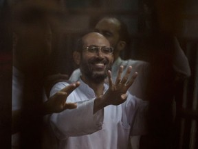 Former employees of the Egyptian presidency under ousted Islamist president Mohammed Morsi give the four-fingered symbol of Rabaah that refers to the deadly dispersal of Morsi supporters in August 2013, inside a defendants cage in a makeshift courtroom at the national police academy, in an eastern suburb of Cairo, Egypt, Saturday, June 18, 2016. An Egyptian court has sentenced six people, including two Al-Jazeera employees, to death for allegedly passing documents related to national security to Qatar and the Doha-based TV network during the rule of Morsi. The former president, the case's top defendant, was also sentenced on Saturday to 25 years in prison. He was ousted by the military in July 2013, and has already been sentenced to death in other cases. (AP Photo/Amr Nabil)