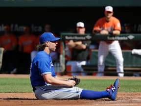 Toronto Blue Jays starting pitcher R.A. Dickey sits on the ground after not being able to tag out Manny Machado as he scored on a passed ball in Baltimore, Saturday, June 18, 2016. (AP Photo/Patrick Semansky)