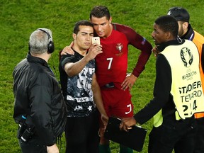 Cristiano Ronaldo poses for a selfie with a man who invaded the pitch at the end of the Euro 2016 match between Portugal and Austria at the Parc des Princes stadium in Paris Saturday, June 18, 2016. (AP Photo/Francois Mori)