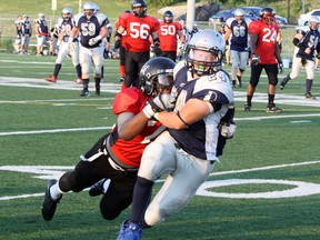 Sudbury Spartans running back Scott Smith (24) is tackled by Oakville Longhorns' Emmanual Songue during Northern Football Conference action at James Jerome Sports Complex in Sudbury on Saturday. Ben Leeson/The Sudbury Star/Postmedia Network