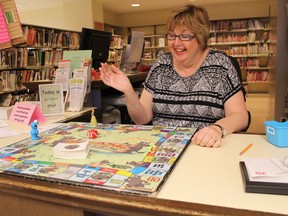 Darlene Pretty at the Woodstock Public Library uses the Wolfie-o-poly board to help choose a new book. The game, similar to monopoly but with a nod to the library's mascot "Wolfie," helps kids expand their reading horizons. Summer reading programs kick off at all the local libraries this month. (MEGAN STACEY/Sentinel-Review)