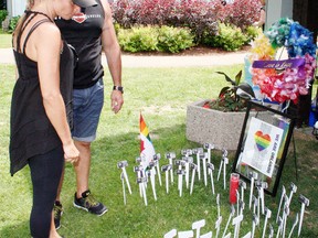 Diana and Bill Lane of Ancaster pause during Oxford's Pride celebration in Southside Park on Saturday to take a moment at a memorial for the 49 people killed in a mass shooting at a nightclub in Orlando, Fla., recently. The white markers included the names and photographs of all those who died. (JOHN TAPLEY/SENTINEL-REVIEW)