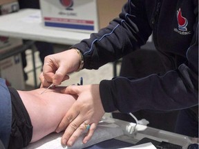 A man gives blood in Montreal, on November 29, 2012. A new blood-donation policy will come into effect across Canada in August. It will allow men who have sex with other men to give blood after a year without doing so, instead of five.  THE CANADIAN PRESS/Ryan Remiorz