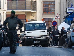 Police officers stand by the police station, seen in background right, after officers shot and killed a knife-wielding man wearing a fake explosives vest,  in Paris, Thursday, Jan. 7, 2016. Officers shot and killed a knife-wielding man wearing a fake explosive vest at a police station in northern Paris on Thursday, French officials said, a year to the day after an attack on the French satirical newspaper Charlie Hebdo launched a bloody year in the French capital. (AP Photo/Michel Euler)