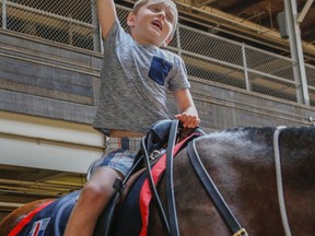 Nolan Russell, 7, son of slain Toronto Police Sgt. Ryan Russell, takes a ride on the  four-year-old Purebred Clydesdale named Russell for his father at the Toronto Police Services Mounted Horse Palace Tuesday, June 21, 2016. (Dave Thomas/Toronto Sun)