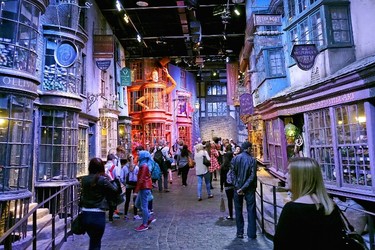 In this May 23, 2015 photo, tourists stroll along the Diagon Alley movie set at The Making of Harry Potter Warner Bros. Studios experience in London. Visitors can view props, costumes and sets, including Platform 9 ¾, the Night Bus, Harry’s cubbyhole at Number 4 Privet Drive and a miniature Hogwarts campus. You can get filmed riding your very own Nimbus 2000, or pile the family into the Weasley invisible car for a group photo. (AP Photo/Ross D. Franklin)