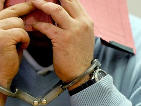 A picture taken on Dec. 9, 2014 shows former nurse Niels H., charged with multiple murder and attempted murder of patients, in handcuffs covering his face with a folder in a courtroom of the regional court in Oldenburg, northern Germany. (INGO WAGNER/AFP/Getty Images)