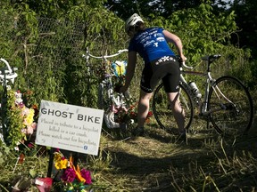 A cyclist takes a moment to place a flower at one of the ghost bikes during the Peace-Pedal-Pray memorial ride in Kalamazoo, Mich. on Sunday, June 12, 2016. The ride honored the five cyclists killed and four injured in a hit-and-run crash on Tuesday, June 7, 2016. Hundreds participated in the 7.5 mile ride that rode part of the route the cyclists had taken that night. (Chelsea Purgahn/Kalamazoo Gazette-MLive Media Group via AP)