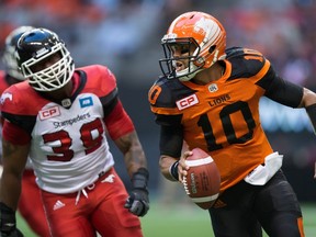 B.C. Lions quarterback Jonathon Jennings, right, is chased by Calgary Stampeders defender Charleston Hughes during a pre-season CFL game in Vancouver Friday June 17, 2016. (THE CANADIAN PRESS/Darryl Dyck)