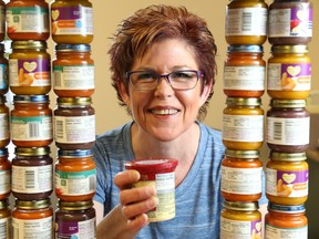 Luke Hendry/The Intelligencer
Program co-ordinator Bev Heuving of the Community Development Council of Quinte holds a container of baby food at the office in Belleville. The council's annual baby-food drive has surpassed its target by more than half. The Good Baby Box program sells discounted baby food and related supplies to clients of any income.