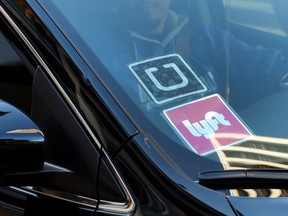 In this Tuesday, Jan. 12, 2016, file photo, a driver displaying Lyft and Uber stickers on his front windshield drops off a customer in downtown Los Angeles. (AP Photo/Richard Vogel, File)