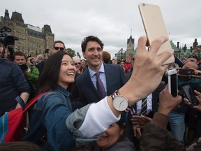 A woman takes a selfie with Prime Minister Justin Trudeau as he walks to his motorcade on Parliament Hill following a group photo of parliamentarians to mark the 150th anniversary of parliament Wednesday June 8, 2016 in Ottawa. (THE CANADIAN PRESS/Adrian Wyld)