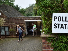 People leave after casting their ballot papers in a polling station set up inside the garage of a residential home in Croydon, south of London on June 23, 2016, as Britain holds a referendum to vote on whether to remain in, or to leave the European Union. (AFP PHOTO/BEN STANSALL)