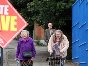 People walk past a "Vote Leave" sign as they arrive to cast their ballots at a polling station in Belfast, Northern Ireland, on June 23, 2016, as the United Kingdom holds a referendum to vote on whether to remain in, or to leave the European Union. (AFP PHOTO/PAUL FAITH)