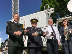 (Left to right) Marty Scott (Executive Director, EMS Provincial Programs, Alberta Health Services), Marianne Ryan (Deputy Commissioner, Alberta RCMP), Brad Grainger (Deputy Chief, Fort McMurray Fire Department) and Kathleen Ganley (Alberta Minister of Justice) hold two-way radios outside the Alberta Legislature in Edmonton on Thursday June 23, 2016. LARRY WONG/Postmedia Network