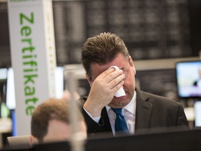 Robert Halver of Baader Bank wipes his face in the trading hall of the Frankfurt, Germany, stock exchange Friday morning, June 24, 2016, after stocks plummeted when Britain voted to exit from the European Union. (Frank Rumpenhorst/dpa via AP)