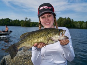 Author Ashley Rae with a largemouth bass caught on opening day of bass season with some nearby boaters cheering her on.
