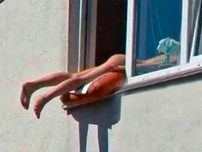 A woman sunbathes out her window in the south-central Russia’s city of Novosibirsk in this undated handout photo. Handout/Postmedia Network