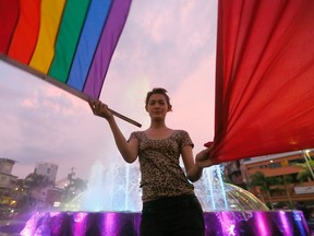 A Filipino LGBT member waves a rainbow flag during a vigil to pay tribute to the victims of the Orlando, Fla. mass shooting Wednesday, June 15, 2016 in Manila, Philippines. A gunman, later identified as Omar Mateen, opened fire inside a crowded Pulse gay nightclub early Sunday in Orlando before dying in a gunfight with responding SWAT officers, authorities said. (AP Photo/Bullit Marquez)
