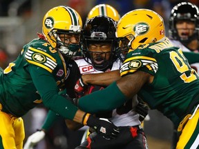 Ottawa Redblacks' William Powell (29) is tackled by Edmonton Eskimos' Dexter McCoil (L) and Don Oramasionwu (R) during the CFL's 103rd Grey Cup championship football game in Winnipeg, Manitoba, November 29, 2015. REUTERS/Mark Blinch